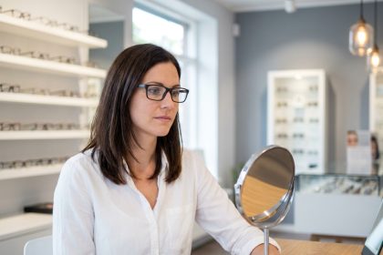 Femme essayant des lunettes chez un opticien moderne, comparant différentes montures pour trouver la correction visuelle adaptée